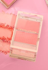 Paleta de rubor de tres tonos en un estuche de plástico transparente. Incluye tonos de rosa, con un patrón texturizado en el pan del medio y un acabado suave en los otros.