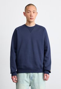 Mørkeblå sweatshirt med rund hals, ribbede manchetter og kant. Fremstillet af blødt bomuld med et subtilt struktureret mønster.