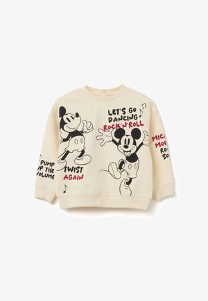 Sweat-shirt crème avec des illustrations de Mickey Mouse dansant et des phrases textuelles telles que « Allons danser », « Rock’n’Roll » et « Re-twist ».