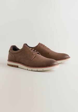 Rjavi usnjeni čevlji z gladko teksturo, zaobljenim prstom, vezalkami in kontrastnim belim gumijastim podplatom z rahlim rjavim odtenkom.