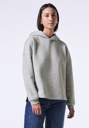 Sudadera gris claro con un corte relajado, textura suave y acentos de rhinestone dispersos, combinada con jeans azul oscuro.