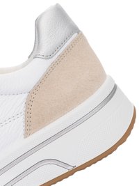 Close-up of white sneaker heel with beige suede patch, silver leather accent, textured white midsole, and gum rubber outsole.