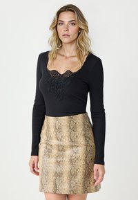 Czarny, prążkowany top z długim rękawem i koronkowymi detalami przy dekolcie, zestawiony z dopasowaną spódnicą w złoty wzór węża. Gładka tekstura i przylegający fason.