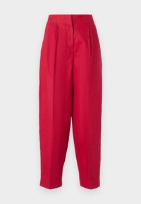 Pantalons en lin rouges avec une taille haute, un devant plissé et des jambes fuselées. Texture lisse et design minimaliste, sans matériel visible ni motifs.