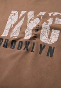 Braunes Baumwolle-T-Shirt mit NYC- und Brooklyn-Grafik in Schwarz und Weiß, mit einer Kartenstruktur in den Buchstaben und abgenutzten Akzenten.