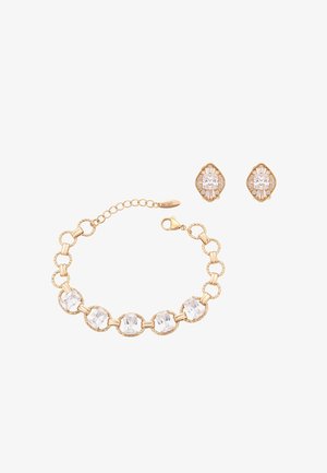 Guldarmbånd med seks store klare ædelsten og matchende guldringe med klare sten i en dekorativ indfatning.