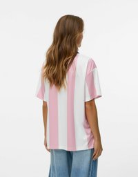 Lyserød og hvid stribet T-shirt med en afslappet pasform, korte ærmer og rund halsudskæring. Glat tekstur, bæres med blå loose-fit jeans.