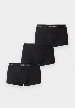 Τρία μαύρα μποξεράκια Calvin Klein με μπράντος στη μέση, τοποθετημένα επικαλυπτόμενα σε λευκό φόντο.