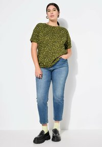 Top corto de estampado de leopardo verde, combinado con jeans azul con corte tapered, calcetines amarillos y zapatos negros gruesos. Diseño simple, ajuste casual.