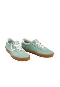 Sneakers de camurça em verde menta com atacadores e língua brancos. Apresenta uma sola de borracha caramelo e um logótipo lateral branco em contraste. Design simples.