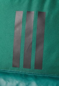 Sac textil verde cu trei dungi verticale negre, finisaj neted și margini cusute. Detalii specifice includ un model texturat.