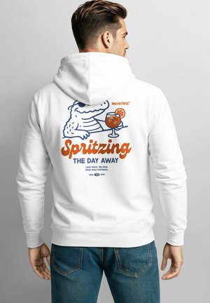 Mann trägt einen weißen Hoodie mit einem Cartoon-Krokodil, das einen Spritz-Cocktail hält, und dem Text "Den Tag mit Spritz verbringen" auf dem Rücken.