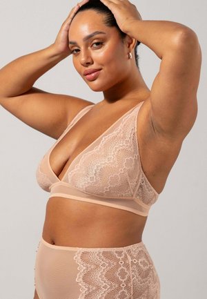 Bralette in pizzo e slip coordinati in morbido beige. Caratterizzato da delicate rifiniture in pizzo floreale, un scollo profondo e spalline larghe.