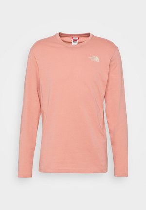 Jasnoróżowa koszulka z długim rękawem i okrągłym dekoltem, z logo The North Face na górnej lewej piersi, prezentowana na jednolitym tle.