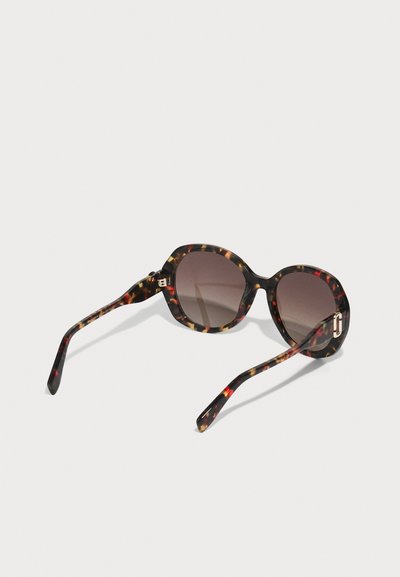 Sonnenbrille im Schildpatt-Muster mit braunen Gläsern. Sie hat ein elegantes, rundes Design und goldene Hardware-Akzente an den Temples.