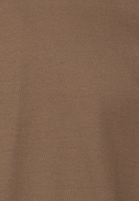 Texture de tissu marron uni avec un motif de maille fine et étroitement tissée, présentant de légers plis naturels.