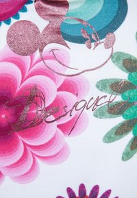 Bílá látka s velkými květinovými vzory v růžové a modrozelené barvě. Součástí je kovově růžový grafik Mickey Mouse a ručně psaný nápis "Desigual".