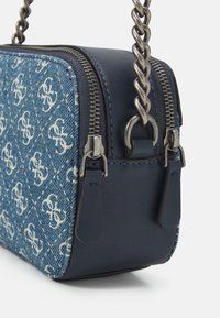 Borsa a tracolla in denim blu con motivi a logo bianchi, hardware in argento, chiusura con zip e tracolla in catena metallica intrecciata.