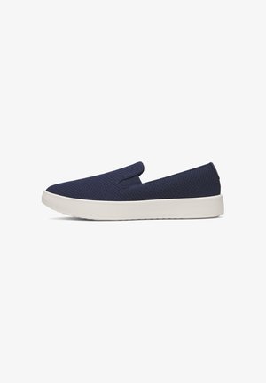 Chaussure slip-on bleu marine avec dessus en tissu texturé et semelle blanche épaisse en caoutchouc, présentée de profil sur fond blanc.