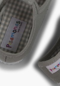Scarpa in tessuto grigio con design piatto. Presenta un motivo a scacchi sulla soletta e un'etichetta del marchio colorata. Cuciture bianche lungo i bordi.