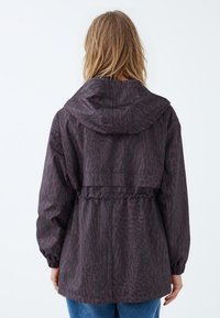 Hooded jack in donkerpaars met een luipaardprint, voorzien van elastische aansnoeringen in de taille en ribbenmanchetten, gemaakt van een lichtgewicht materiaal.