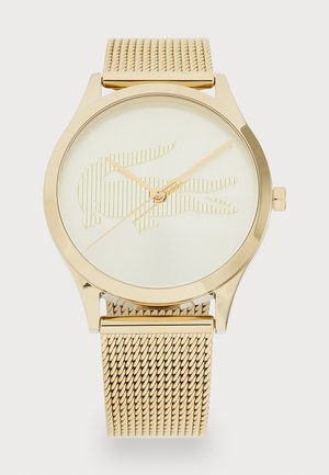 Montre dorée avec un bracelet en maille, dotée d'un cadran crème minimaliste et d'un motif logo en relief. Aiguilles et logo dans une finition dorée assortie.