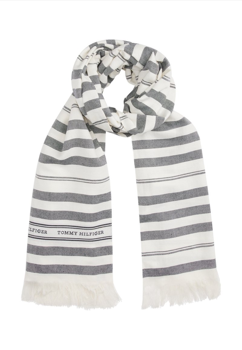 Écharpe blanche avec des rayures noires horizontales et des extrémités à franges, avec le texte "Tommy Hilfiger" près d'une extrémité.