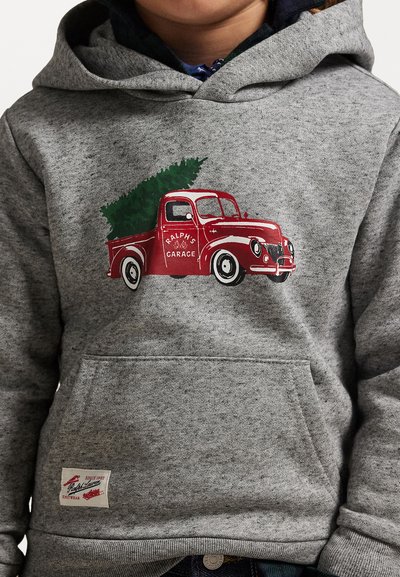 Siva kapuca z značko s grafiko rdečega vintage tovornjaka z božičnim drevesom, z detajlom žepa in blagovno oznako na robu.