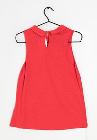 Vestito rosso senza maniche con colletto, caratterizzato da un dettaglio a chiave sulla schiena e un motivo floreale testurizzato. Appeso a una gruccia di metallo nero.