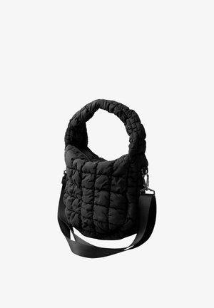 Czarna pikowana torebka z tkaniny z wyściełanym uchwytem górnym i odpinanym paskiem na ramię, na białym tle.