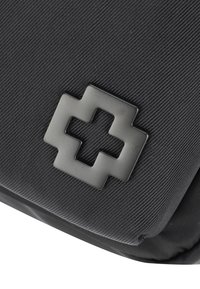Borsa nera in nylon con superficie texturizzata e un evidente emblema a croce nero opaco. Il design è elegante e funzionale.