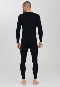 Sort termisk langærmet top og leggings lavet af strækstof. Glat tekstur med subtile mesh-detaljer på bagsiden. Simpelt design.