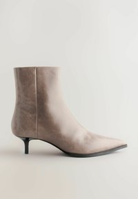 Bottine en cuir marron clair, avec un bout pointu, un design élégant et un talon aiguille fin pour un look moderne.