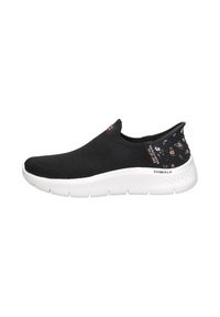 Zapatilla negra sin cordones con un upper texturizado, suela blanca y acentos de patrón floral en el talón. Diseño ligero y flexible.