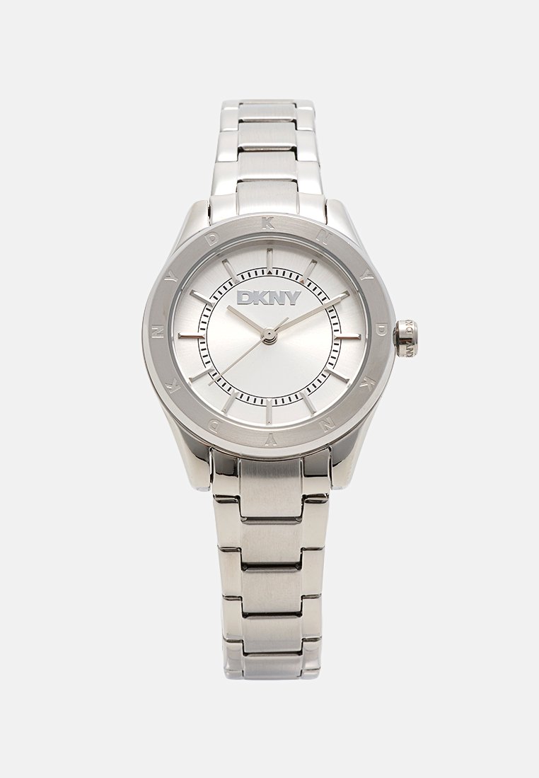 Silberner Edelstahl-Armbanduhr mit rundem Ziffernblatt, das über ein metallisches silbernes Ziffernblatt und gravierte Stundenmarker verfügt. DKNY-Logo prominent platziert.