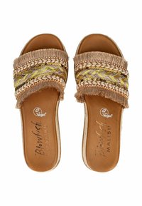 Sandali vegani con suola piatta, caratterizzati da una base marrone chiaro e un design di cinturini intrecciati in crema, giallo e dettagli metallici. Bordo frangiato.
