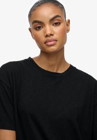 Sort crew neck t-shirt lavet af bl�ødt, struktureret stof med kortærmer og et subtilt logo på brystet. Enkel og afslappet pasform.