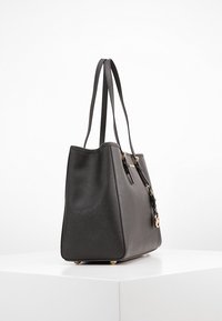 Borsa a tracolla nera in pelle con finitura testurizzata, accessori in oro e due manici. Presenta un accento con portachiavi e piedi protettivi.
