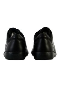 Sneaker nere in pelle con finitura liscia, retro arrotondato e design minimalista. Presentano il logo sul tallone e suola in gomma nera semplice.