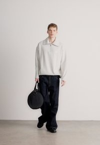 Γκρι ανοιχτό φερμουάρ φλις φούτερ, σκούρο μπλε φαρδιά τζιν και στρογγυλή μαύρη τσάντα ώμου. Λείες υφές και άνετη εφαρμογή.