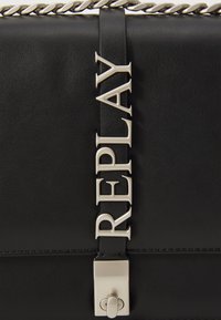 Fekete műbőr kézitáska ezüst színű záródással és olyan pánttal, amelyen nagy, figyelemfelkeltő betűkkel van írva, hogy "REPLAY."