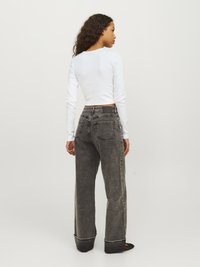 Top bianco a maniche lunghe abbinato a jeans a gamba larga grigi scuri a vita alta con cuciture a contrasto e orli arrotolati.