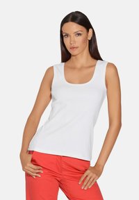 Witte tanktop van ribstop met een ronde halslijn, gecombineerd met rode broek, met een ontspannen pasvorm en zonder zichtbare patronen of accenten.