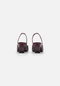 Burgundy lakkbőr slingback cipők négyzetformájú sarokkal, sima textúrával és minimalista designnal, hátsó nézetből.