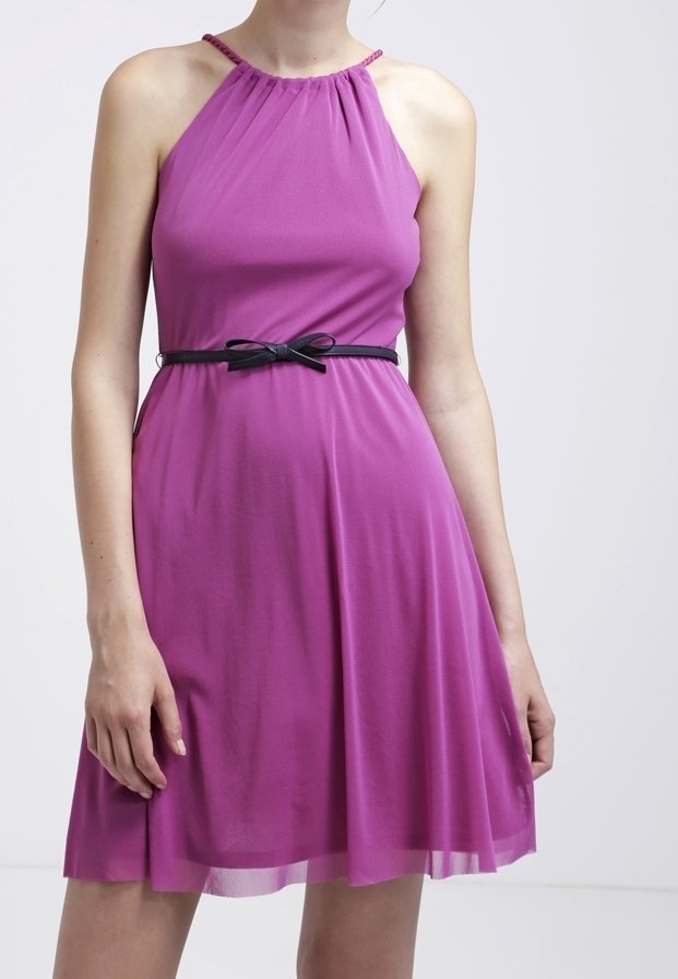 Femme portant une robe violette sans manches, longueur genou, avec un col halter et une fine ceinture noire nouée en nœud à la taille.