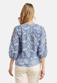 Blauw-witte blouse met patroon, voorzien van ballonmouwen, een geplooide achterkant en een losse pasvorm, gemaakt van lichtgewicht stof.