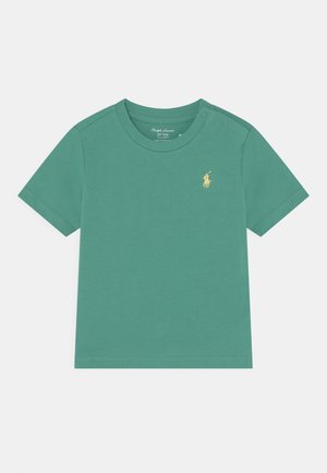 Zielona koszulka z krótkim rękawem z bawełnianego materiału z okrągłym dekoltem. Posiada małe, żółte, haftowane logo na piersi. Miękka tekstura.