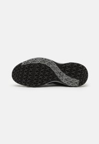 Suela de zapato atlético negra con una superficie de goma texturizada, que presenta un acento gris y un diseño de patrón cruzado para mayor agarre y durabilidad.