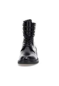 Botte de combat en cuir noir à lacets avec œillets métalliques, cheville haute et semelle épaisse, montrée de face sur fond blanc.