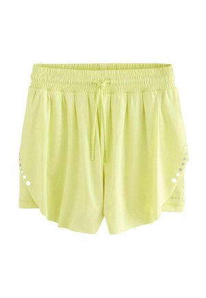 Jasnożółte spodenki sportowe z elastycznym pasem, sznurkiem do regulacji i dekoracyjnymi okrągłymi wycięciami po bokach. Miękka, gładka tekstura.
